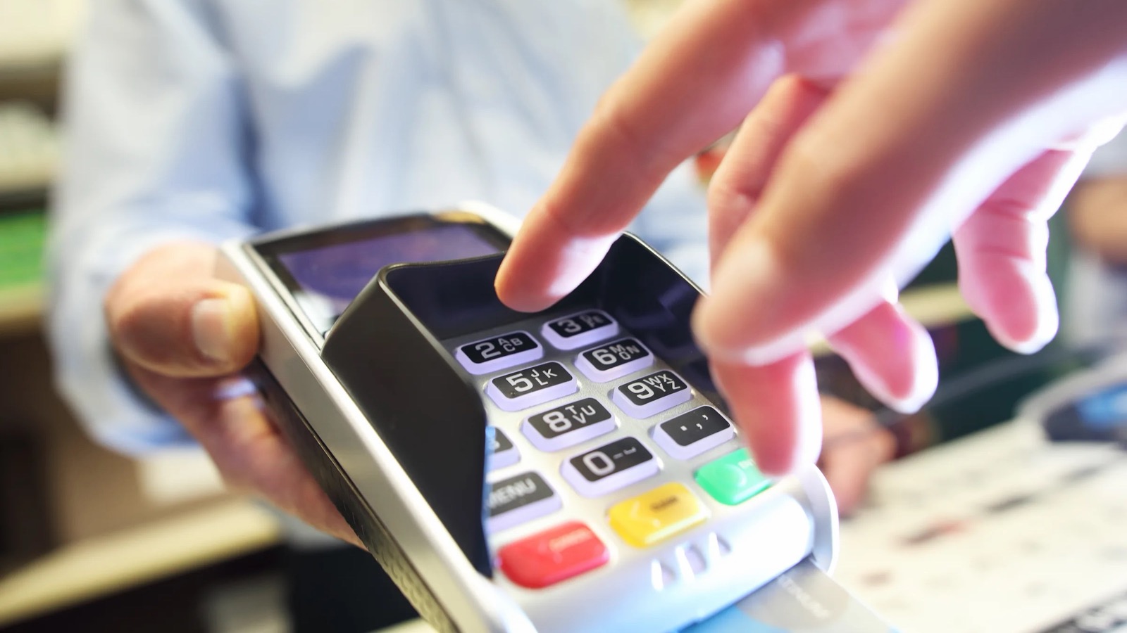 Customer entering a PIN on a card terminal at the counter